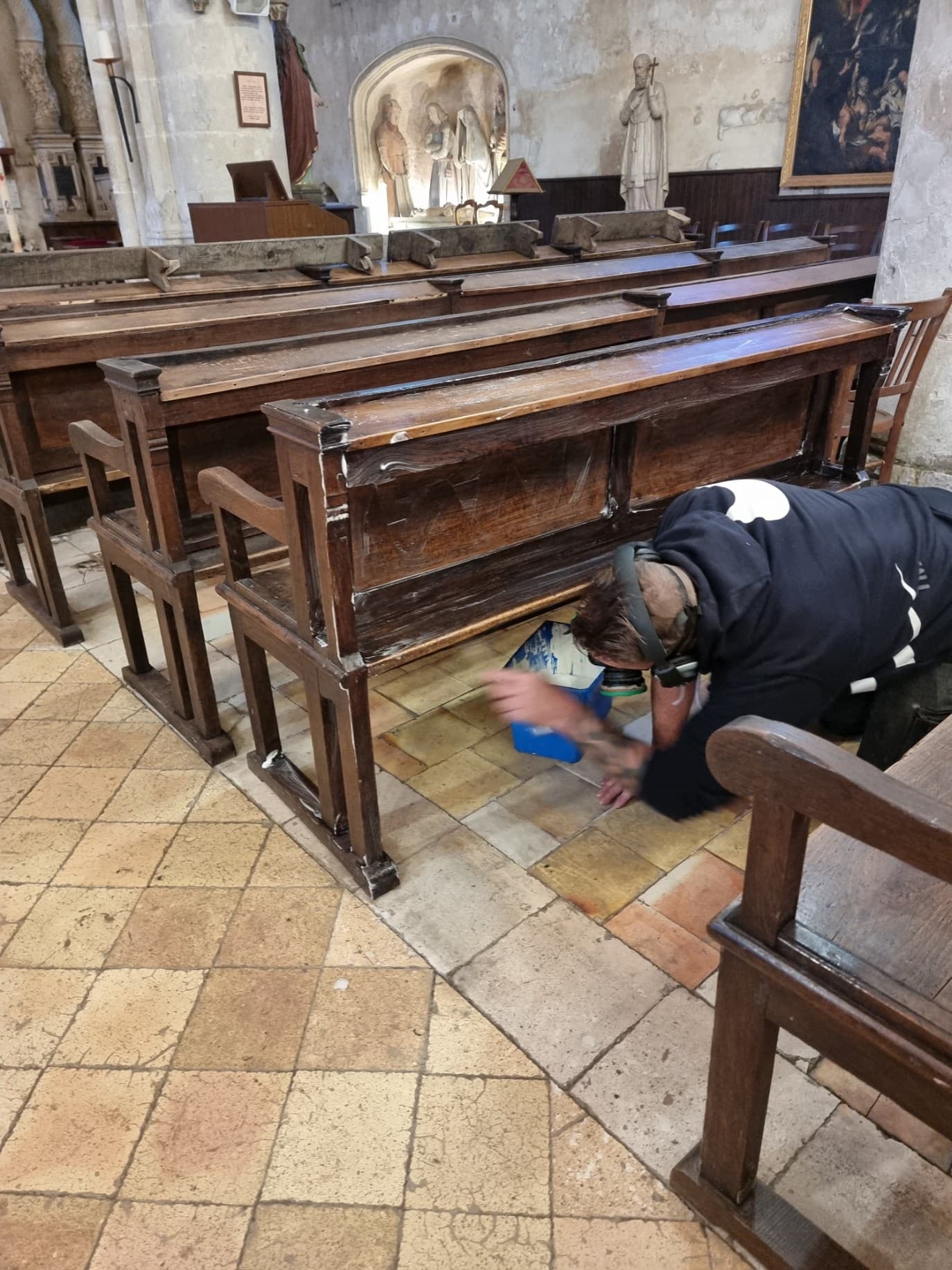 Technicien traitant les bancs d'eglise avec equipement de protection